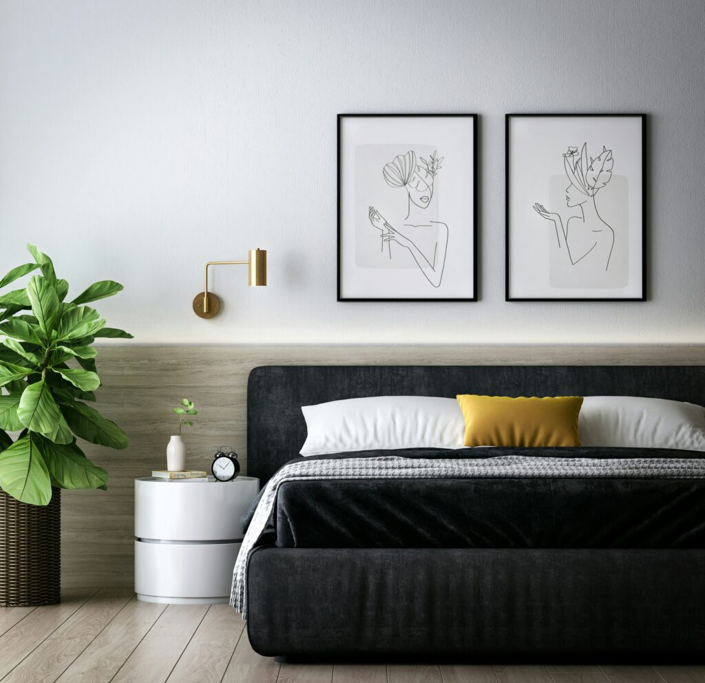 Staged bedroom with black upholstered bed, yellow cushion and line art wall hung print